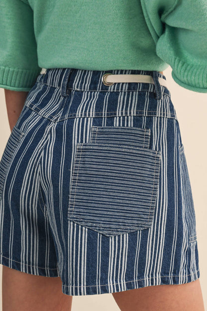 Close up of a rear view of navy and white striped skirt worn with a green sweater on a beige background