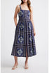 A woman wearing a navy blue bandana-patterned cotton-linen midi dress with a square neckline, adjustable straps, and a button-front skirt.