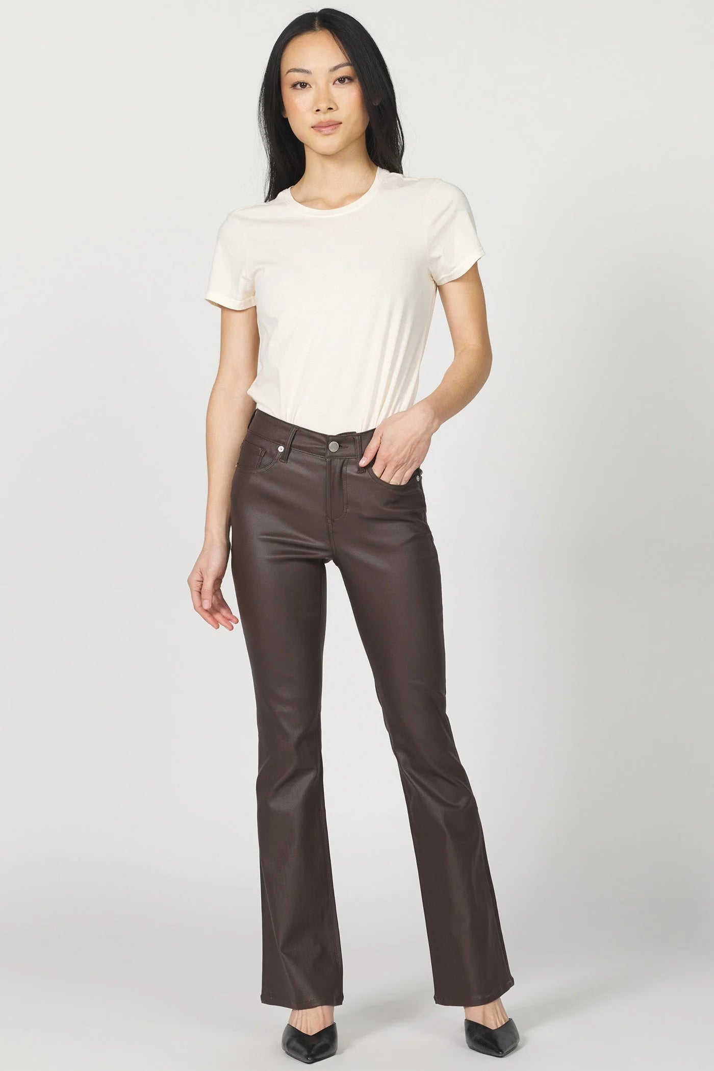 Woman wearing a white t-shirt and brown leather pants on a white background
