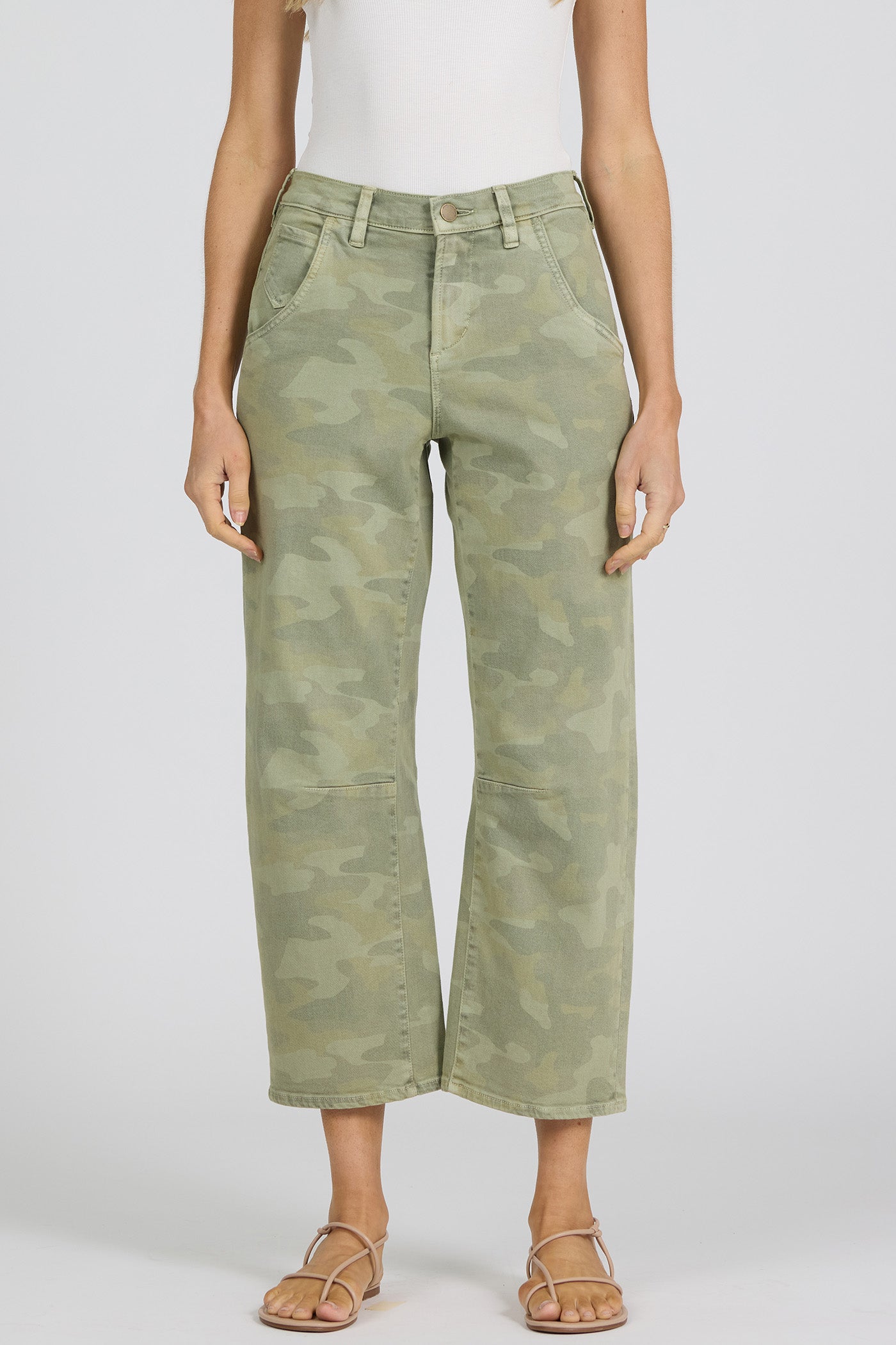Close up of a woman wearing green camouflage pants on a white background.