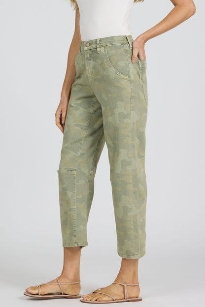 Side view of a woman wearing green camouflage pants on a white background.