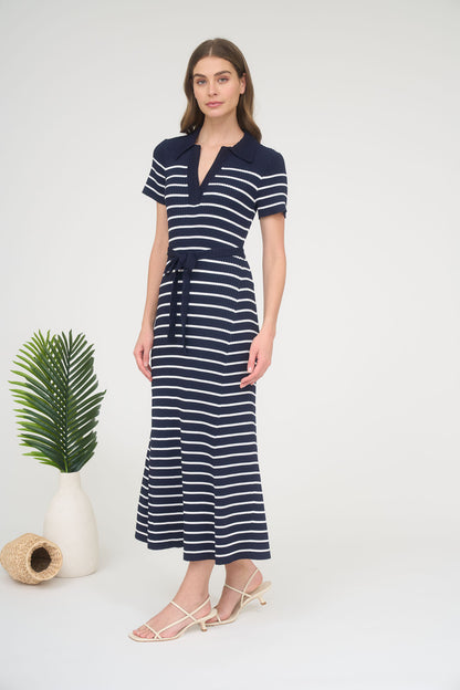 A woman wearing a short-sleeve navy and white horizontally striped ribbed knit maxi dress with a spread collar, split neck, and matching tie belt.