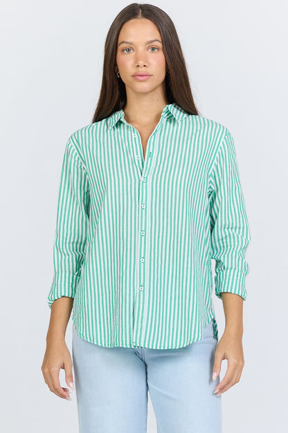Front view of a woman wearing a green and white vertical striped long-sleeve cotton button-up shirt with light blue jeans.