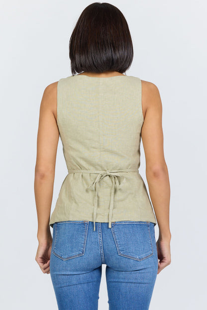 Rear view of a woman wearing a sage green linen-blend sleeveless vest with a tie back and blue jeans