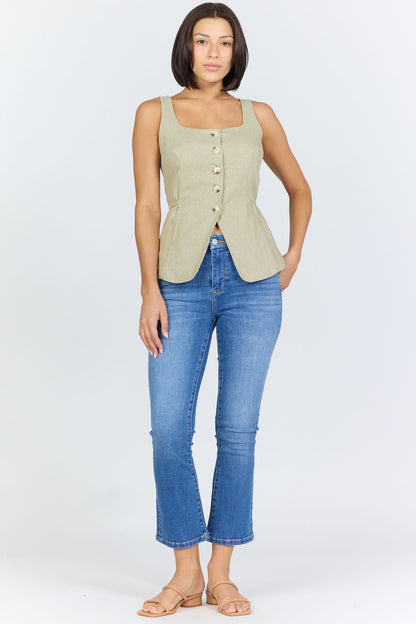 Full body view of a woman wearing a sage green linen-blend sleeveless vest with a button front and blue jeans