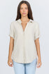 Front view of a model wearing a neutral cream linen-blend short sleeve button-down shirt with light blue jeans.