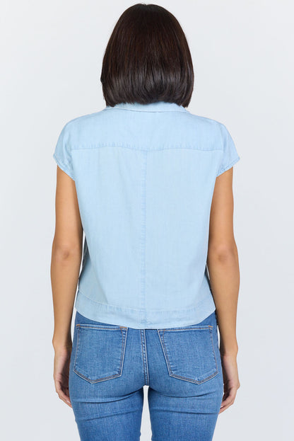 Rear view of a woman wearing a light blue 100% Tencel boxy camp collar shirt with blue jeans.