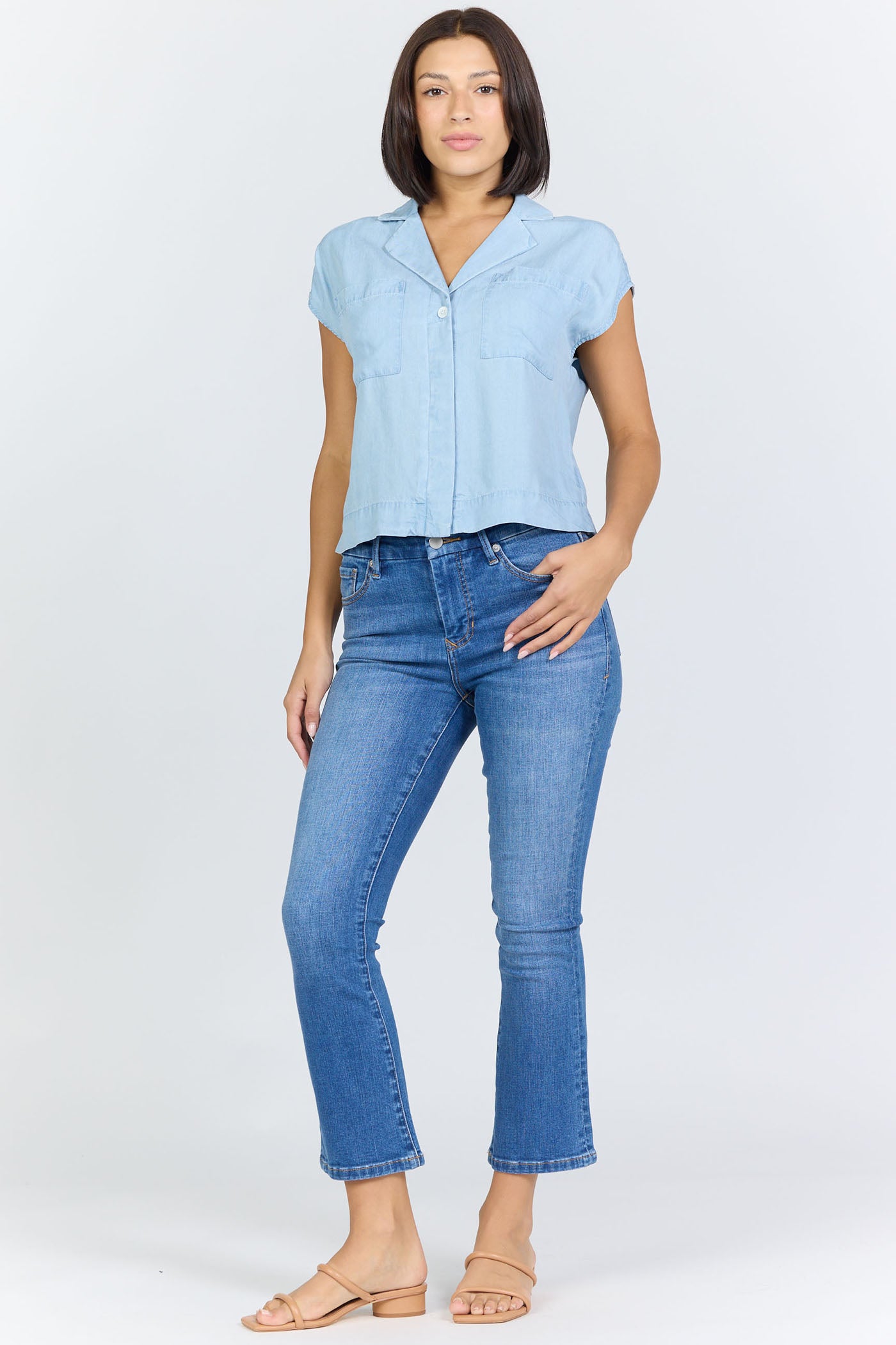 Full body view of a woman wearing a light blue 100% Tencel boxy camp collar shirt with blue jeans.