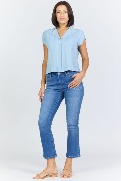 Full body view of a woman wearing a light blue 100% Tencel boxy camp collar shirt with blue jeans.