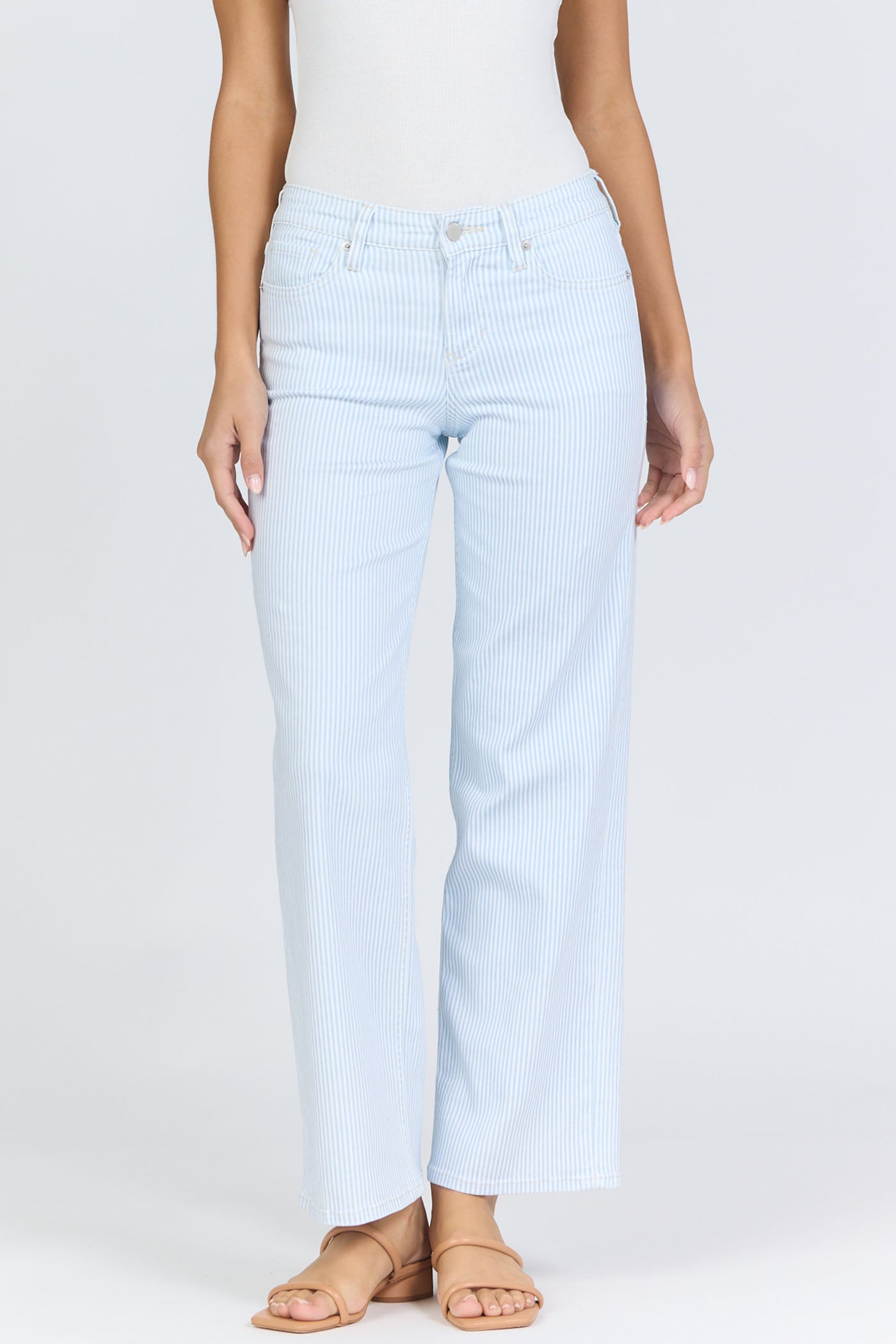 Front view of a woman wearing light blue pinstripe straight-leg jeans with a mid-high rise waistband and a white tank top.