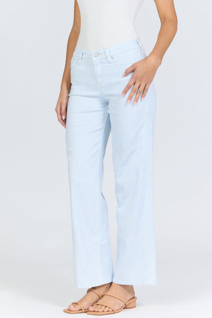 Side view of a woman wearing light blue pinstripe straight-leg jeans with a mid-high rise waistband and a white tank top.