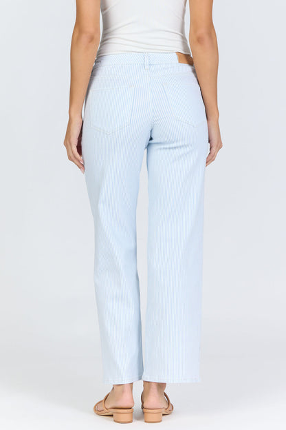 Rear view of a woman wearing light blue pinstripe straight-leg jeans with a mid-high rise waistband and a white tank top.