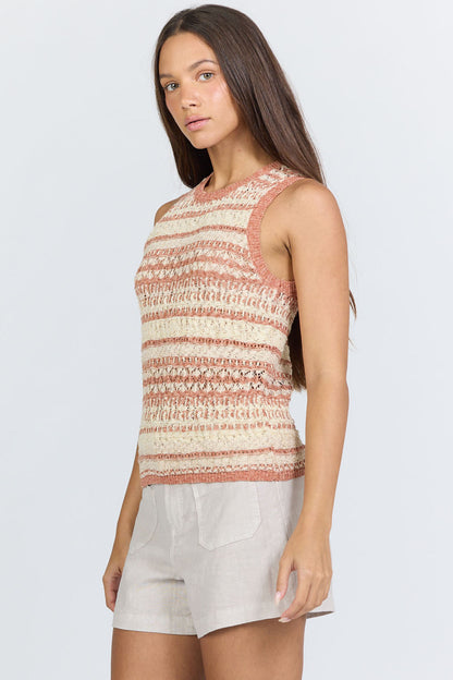 Side view of a woman wearing a sleeveless crew-neck sweater tank with terra-cotta and ivory horizontal stripes, paired with light linen shorts.