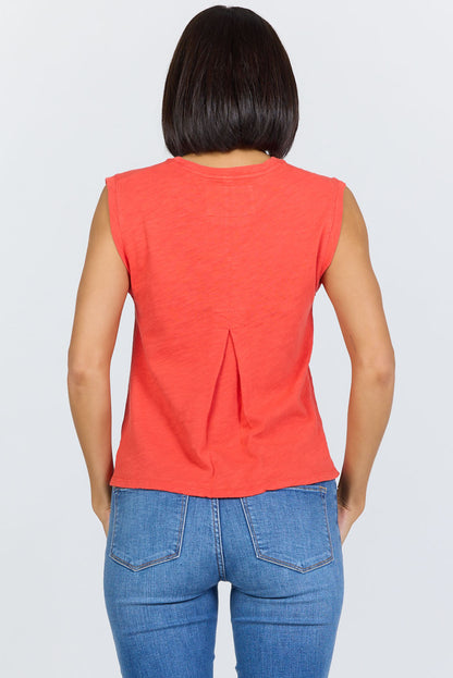 Rear view of a woman wearing a poppy red sleeveless crew neck muscle tank made from textured slub cotton, paired with blue jeans.