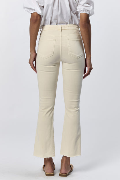 Rear view of a woman wearing the cream mid-rise raw hem flare jeans with gold hardware and a white top.