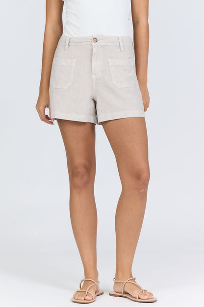 Front view of a woman wearing oatmeal-colored high-rise linen-blend shorts with patch pockets and matching tan strappy sandals.