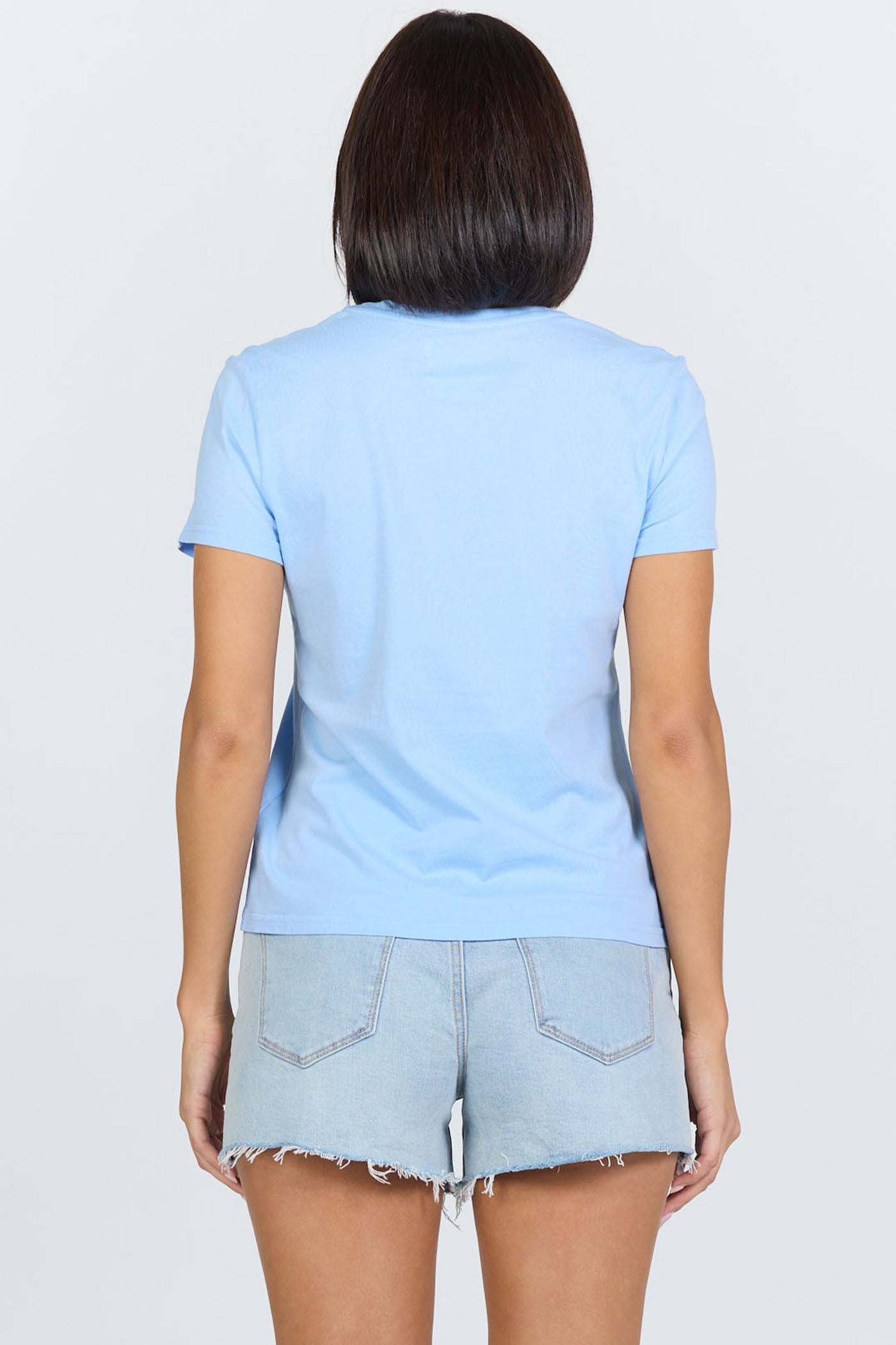 Rear view of a woman wearing a blue classic short-sleeve crew neck cotton jersey t-shirt paired with denim