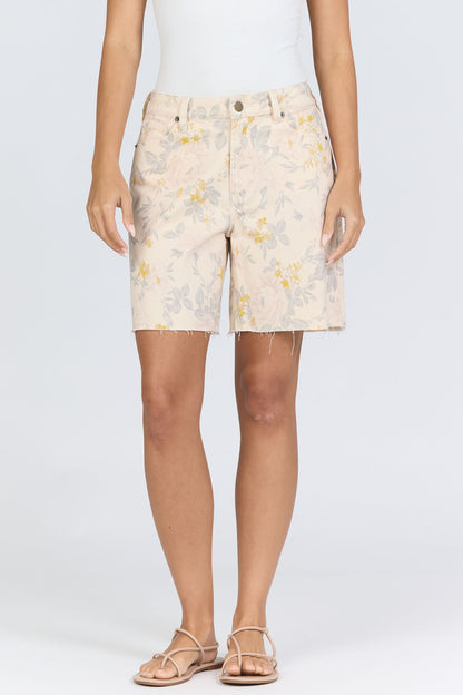 Front view of a model wearing cream vintage floral high-rise denim shorts with flat tan sandals.