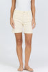 Front view of a woman wearing cream-colored high-rise denim Bermuda shorts with flat tan strappy sandals.