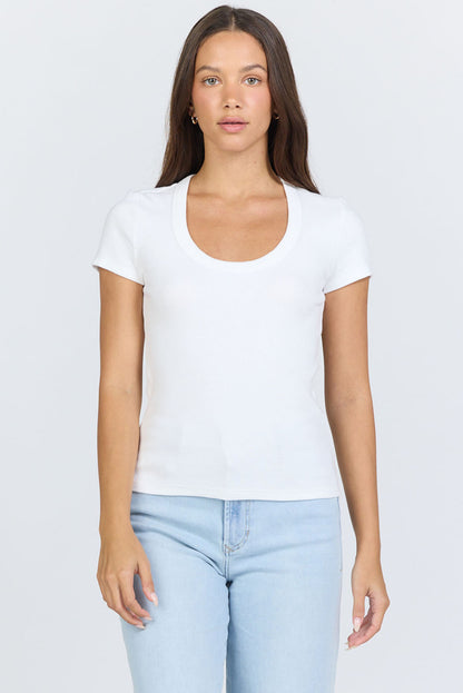 A woman wearing a fitted white scoop-neck short-sleeve t-shirt tucked into blue jeans.