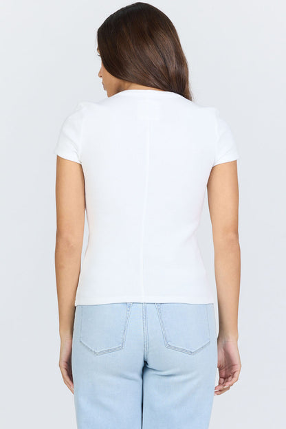 Rear view of a woman wearing a fitted white scoop-neck short-sleeve t-shirt tucked into blue jeans.