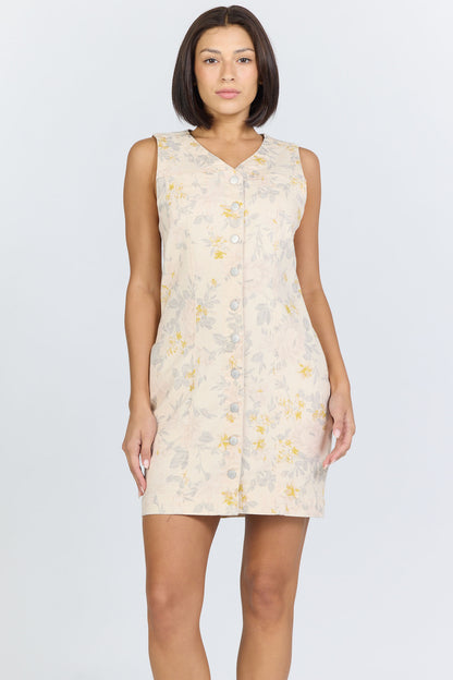 Front view of a model with short dark hair wearing a cream floral button-front sleeveless dress.