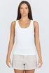 A woman wearing a fitted white scoop-neck ribbed racerback tank top with beige linen shorts.