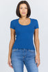 A woman wearing a fitted blue scoop-neck short-sleeve t-shirt tucked into blue jeans.