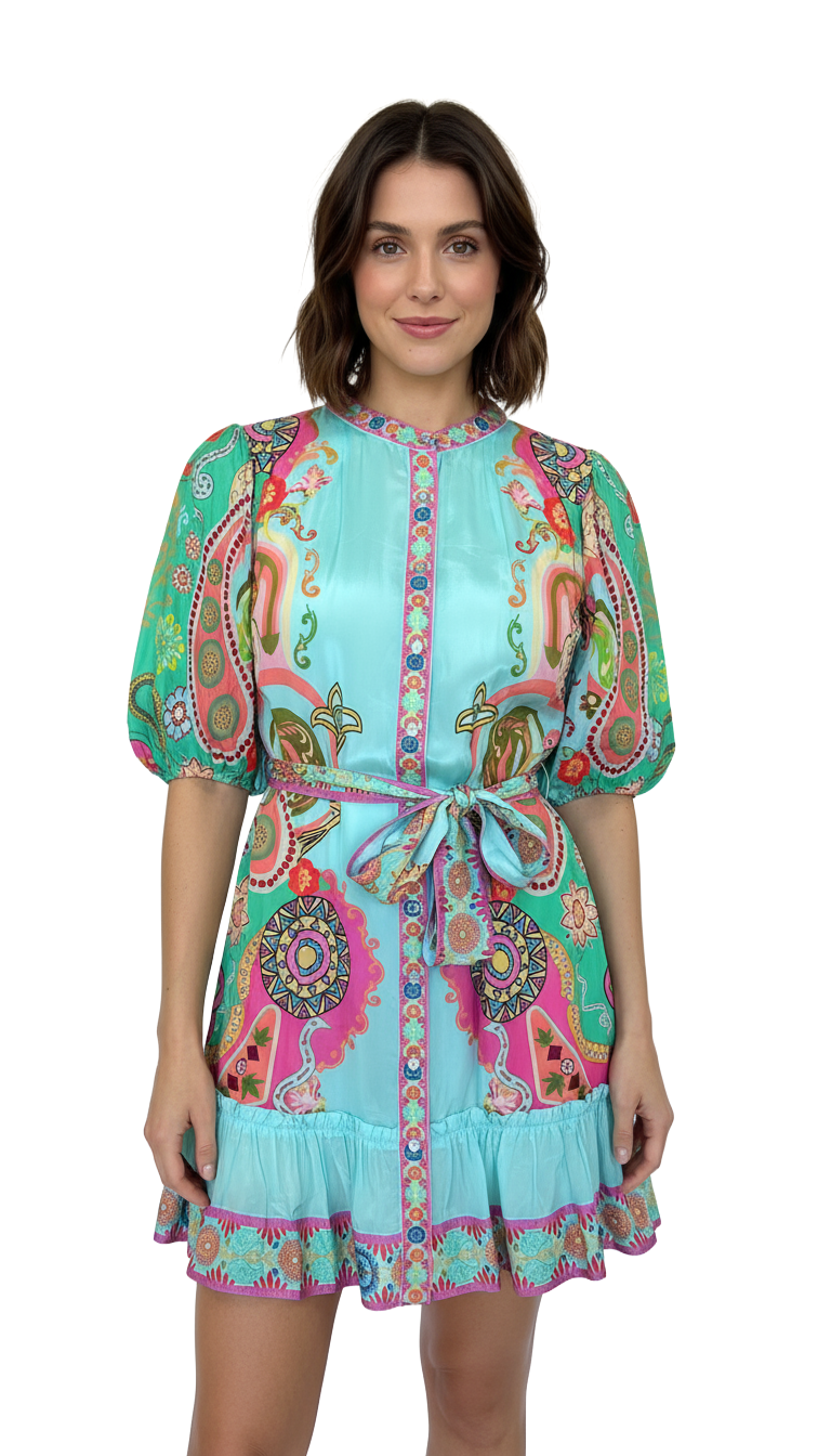 Woman wearing a colorful turquoise paisley mini dress with puff sleeves and a matching tie waist belt.
